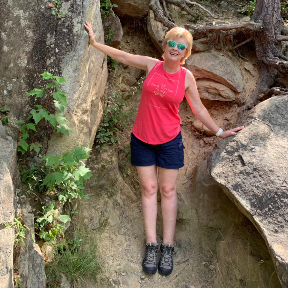 Karen smiling outdoors near large rocks in Western North Carolina